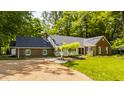 Beautiful exterior view of a red brick home with a manicured lawn and a gravel driveway framed by mature trees at 535 W 93Rd St, Indianapolis, IN 46260