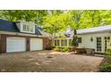View of a two-car garage attached to a red brick home with gravel driveway and rear exterior entrance at 535 W 93Rd St, Indianapolis, IN 46260
