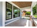 Covered front porch featuring wood ceiling, brick pillars, and large windows at 5682 Broadway St, Indianapolis, IN 46220