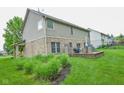 The back exterior shows a multi-level home with siding and a brick patio, along with an expansive lawn at 7322 Stones River Dr, Indianapolis, IN 46259