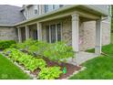 Inviting front porch area with brick columns, landscaping, and a hanging swing for relaxation at 7322 Stones River Dr, Indianapolis, IN 46259
