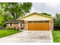 View of a brick house and light brown garage door with green lawn and driveway at 7580 Sherry Ln, Brownsburg, IN 46112