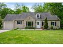 Charming home featuring a manicured lawn and stone detailing around the front picture window at 7910 N College Ave, Indianapolis, IN 46240
