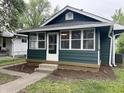 Charming home with a dark green exterior and a sunny, glass enclosed, front porch at 946 N Somerset Ave, Indianapolis, IN 46222
