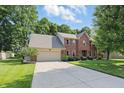 Inviting two-story brick home featuring an attached garage and a spacious driveway surrounded by green grass at 10418 Forest Creek Dr, Indianapolis, IN 46239