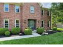 Welcoming front entrance with beautiful landscaping, black mulch, and a classic brick facade at 10418 Forest Creek Dr, Indianapolis, IN 46239