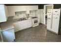 Traditional kitchen features white cabinets, appliances, and worn vinyl flooring at 1164 Groff Ave, Indianapolis, IN 46222