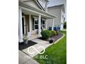 Charming covered front porch with black mulch landscaping beds, trimmed bushes, seasonal flowers, and tasteful decorations at 12993 E 131St St, Fishers, IN 46037