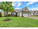 Beautifully landscaped front yard featuring a healthy green lawn, decorative trees, and a three car garage at 1334 Sunnybrook Ln, Greenwood, IN 46143