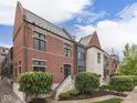 Charming exterior of brick and stone townhouse, featuring beautiful landscaping and classic architectural details at 222 N East St # 103, Indianapolis, IN 46204