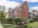 Beautiful rear exterior of the townhouse with manicured landscaping and mature trees at 222 N East St # 103, Indianapolis, IN 46204