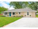 Well maintained exterior with a blue door, manicured bushes and concrete driveway at 3027 Griffa Ave, Columbus, IN 47203