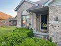Inviting entryway of brick home featuring a decorative door, green shrubbery, and well-maintained landscaping at 3037 Ash Way, Lapel, IN 46051