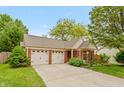 Inviting single-story home with a double garage, landscaped yard, and classic brick accents at 3754 Smallwood W Ln, Indianapolis, IN 46214