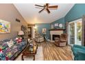 Cozy living room featuring a fireplace, ceiling fan, vaulted ceiling, and updated flooring at 3754 Smallwood W Ln, Indianapolis, IN 46214