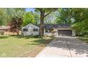 Attractive single-Gathering home featuring a concrete driveway, lush lawn, and mature trees at 5843 N Oakland Ave, Indianapolis, IN 46220