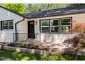 Inviting front entry featuring a lovely garden bed, stone accents, and a modern black door at 5843 N Oakland Ave, Indianapolis, IN 46220