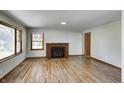 Inviting living room featuring hardwood floors, a cozy brick fireplace, and abundant natural light from large windows at 5941 North St, Stilesville, IN 46180