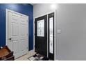 Stylish entryway featuring a decorative front door, blue accent wall, and tile flooring at 6822 Woodford Ln, Indianapolis, IN 46237