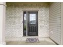Close-up of the front door with decorative glass, brick surround, and stylish welcome mat at 6822 Woodford Ln, Indianapolis, IN 46237