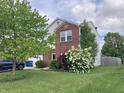 A well-manicured front yard with flowering bushes, a mature tree, and a partial view of the home's brick facade at 6824 W Philadelphia Dr, McCordsville, IN 46055