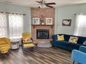 Cozy living room with a brick fireplace, ceiling fan, wood flooring, and stylish furnishings at 6824 W Philadelphia Dr, McCordsville, IN 46055