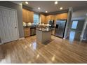 Bright kitchen with wood floors, an island, stainless steel appliances, and tan cabinetry at 6924 Havenmoor Pl, Indianapolis, IN 46250