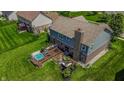 Aerial view of a home's backyard featuring a wooden deck, a hot tub, and lush green lawn at 7320 Corwin Ct, Indianapolis, IN 46259