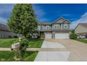 Charming two-story home featuring a landscaped front yard and a three-car garage and a yellow front door at 7320 Corwin Ct, Indianapolis, IN 46259
