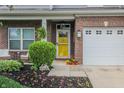 Inviting front entrance with a yellow door, brick accents, and charming landscaping, offering curb appeal at 7320 Corwin Ct, Indianapolis, IN 46259