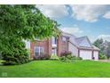Charming two-story brick home with lush green lawn, mature trees, and three-car garage at 13145 Roma Bnd, Carmel, IN 46074