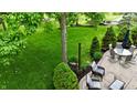 Landscaped backyard featuring an outdoor seating area, mature trees, and lush green grass at 3251 Amber Way, Bargersville, IN 46106