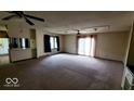Spacious living room featuring plush carpeting, a ceiling fan, and sliding doors to patio at 3702 Candy Cane Dr, Indianapolis, IN 46227