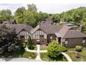 Aerial view of townhome complex with mature trees, landscaped grounds, and well-maintained roofs at 3852 Knollton Rd # 3852, Indianapolis, IN 46228