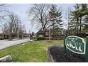Gated community entrance featuring a sign, American flag, guardhouse, and mature trees at 3852 Knollton Rd # 3852, Indianapolis, IN 46228