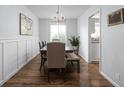 Elegant dining room featuring wood floors, wainscoting, modern lighting, and a view of the backyard, perfect for gatherings at 469 Ash Dr, Carmel, IN 46032