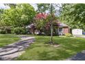 Lovely home with a paved driveway, lush green lawn, and beautiful mature trees in a serene setting at 7734 Hoover Rd, Indianapolis, IN 46260