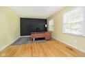 Home office features hardwood flooring, a chalkboard wall, and a modern desk setup by a window at 7734 Hoover Rd, Indianapolis, IN 46260