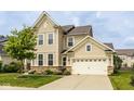 Classic two-story home boasting a two-car garage, beige siding, stone veneer, and a well-maintained lawn at 7824 Hedgehop Dr, Zionsville, IN 46077