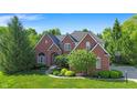 Charming brick two story home with dark roof, manicured lawn, and detailed landscaping at 10390 Tremont Dr, Fishers, IN 46037
