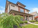 A charming two-story home boasts a covered front porch, landscaped yard, and unique architectural details at 1048 St Peter St, Indianapolis, IN 46203