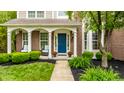 Inviting front porch with chairs, lush landscaping, and a bright blue front door for curb appeal at 11674 Timken Ct, Fishers, IN 46037