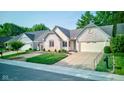 Attractive brick home with manicured lawn and a two-car garage, nestled in a well-kept neighborhood at 12258 Charing Cross Rd, Carmel, IN 46033