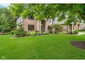 Charming brick home boasts a well-manicured lawn and picturesque landscaping at 12563 Sandstone Run, Carmel, IN 46033