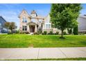 Traditional home with brick and siding, complemented by a green lawn and mature tree at 15580 Garrano Ln, Fishers, IN 46040