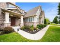 Inviting front porch with hanging flower baskets and manicured landscaping along walkway at 15580 Garrano Ln, Fishers, IN 46040