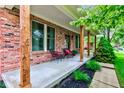 Cozy covered porch featuring wooden pillars, brick facade, and comfortable seating at 1649 Woodstock Dr, Brownsburg, IN 46112