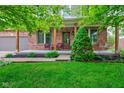 Charming front porch with brick pillars, seating area, and lush landscaping at 1649 Woodstock Dr, Brownsburg, IN 46112