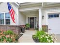 Inviting front porch with colorful flowers and an American flag creating a welcoming entrance at 247 Verdant Dr, Cicero, IN 46034