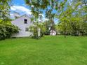 Expansive back yard with lush green lawn, mature trees, and a view of the home's exterior at 2606 Raible Ave, Anderson, IN 46011